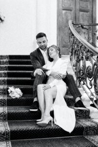 a bride and groom taking a moment to themselves while sitting on some stairs